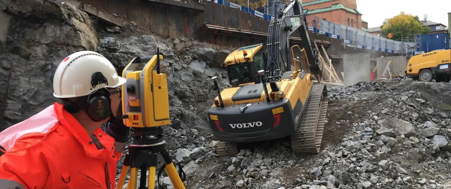 Mättekniker med totalstation vid schakt och grävmaskin